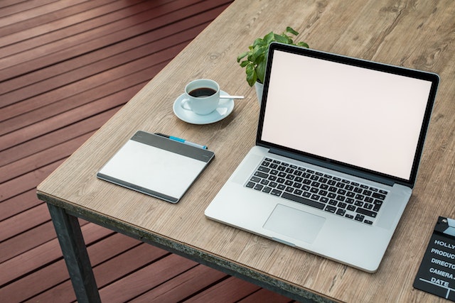 a laptop open on a desk with a cup of coffee and a touchpad